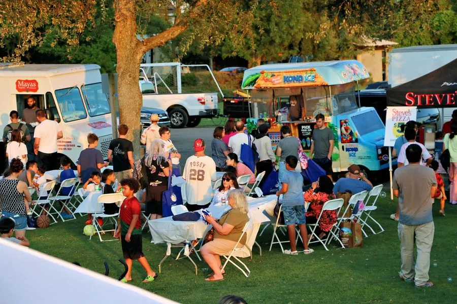 Food trucks and vendor tents glowing in golden light at a Davis community event